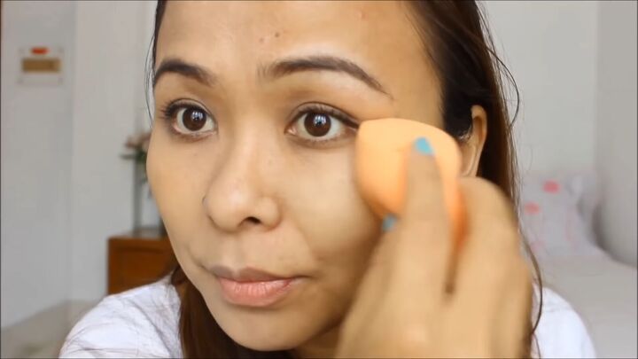 Woman applying foundation swatches on her jawline to find the right shade for her skin tone.